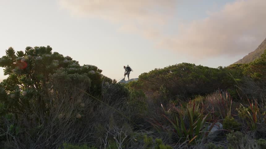 Person standing on a hilltop wearing a backpack