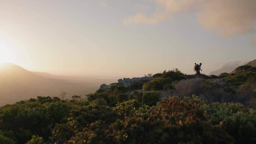 Man hikes in mountains at sunset
