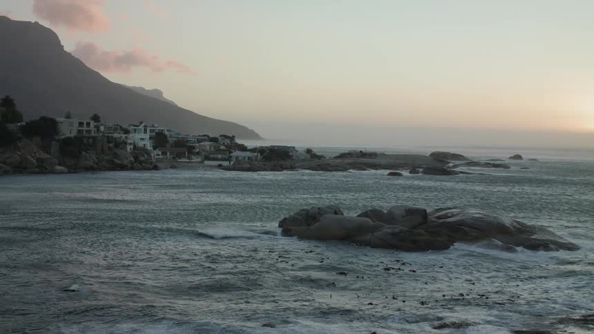 Waves roll around the rocks under a blue sky
