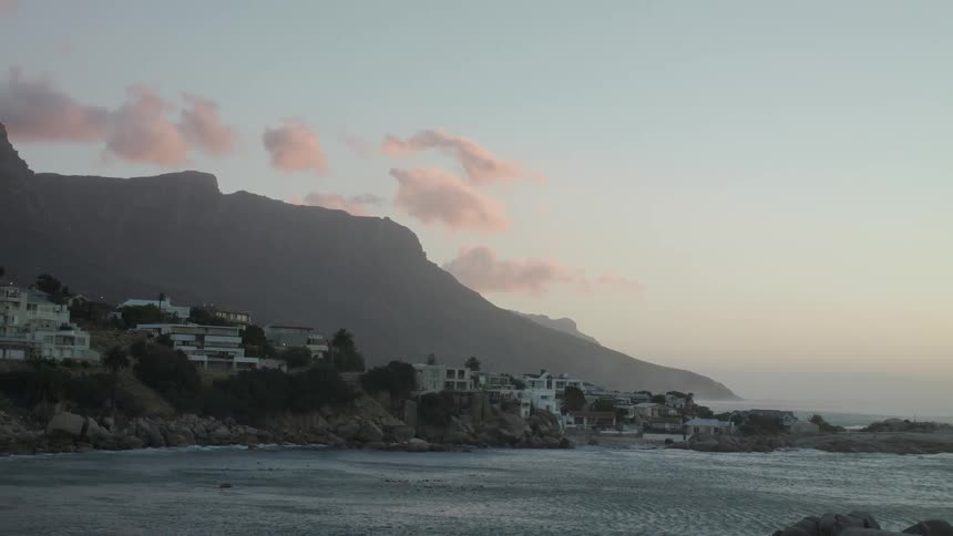 The large homes are behind the rocks near the shore