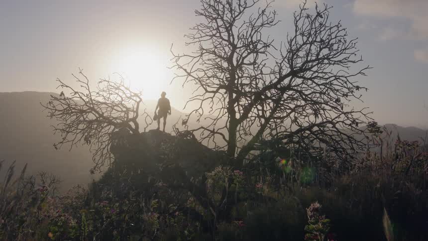 Hiker stands in mountains at sunset