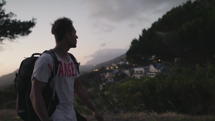 Man hikes in mountains at sunset