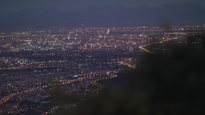 Lights from a city glimmer below a hill
