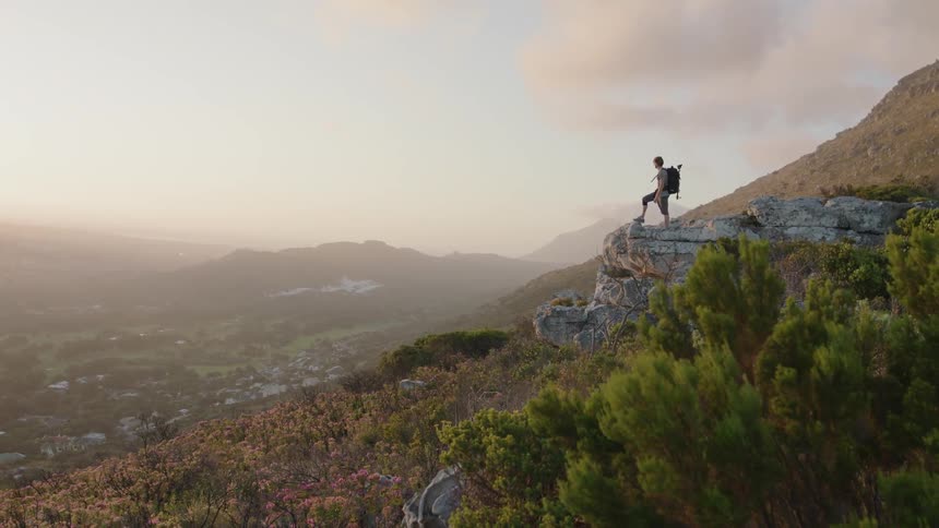 Man hikes in mountains at sunset