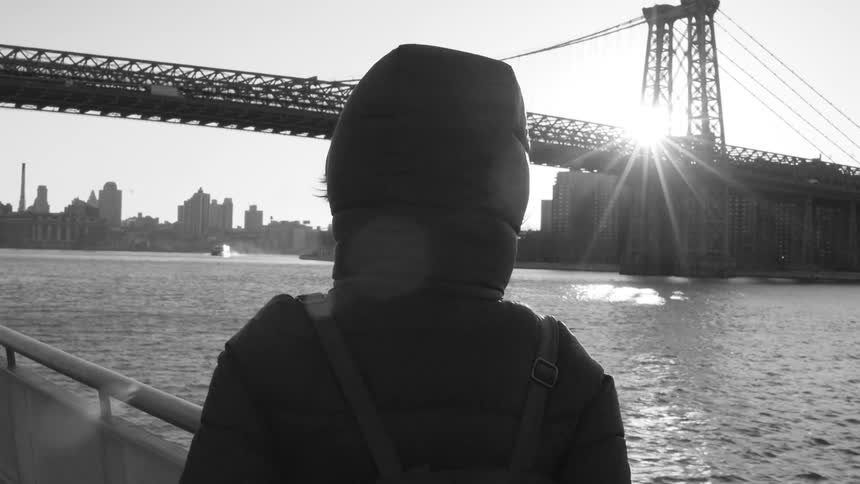 Person traveling on a boat viewing the bridge and city across the water