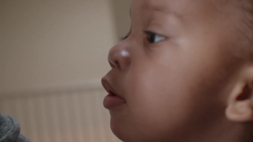 Baby looks to the side while and adult slaps a hand on the wall