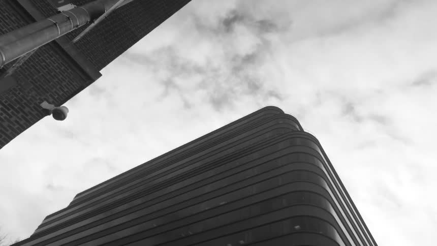 Looking up the tall buildings and into a cloudy sky