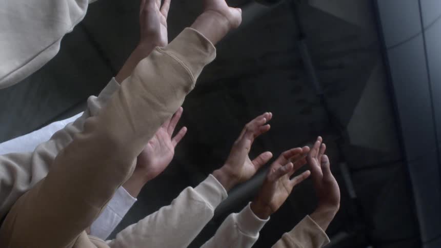Several arms and hands wave in the air