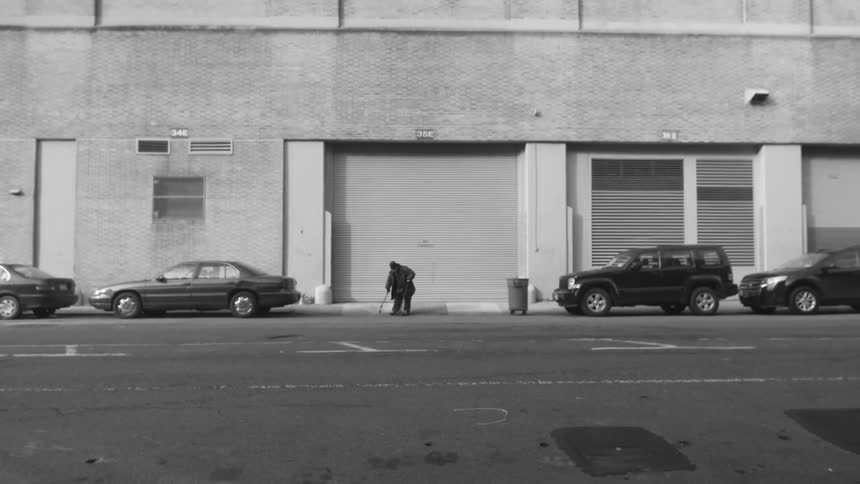 Man sweeping a sidewalk in front of a warehouse