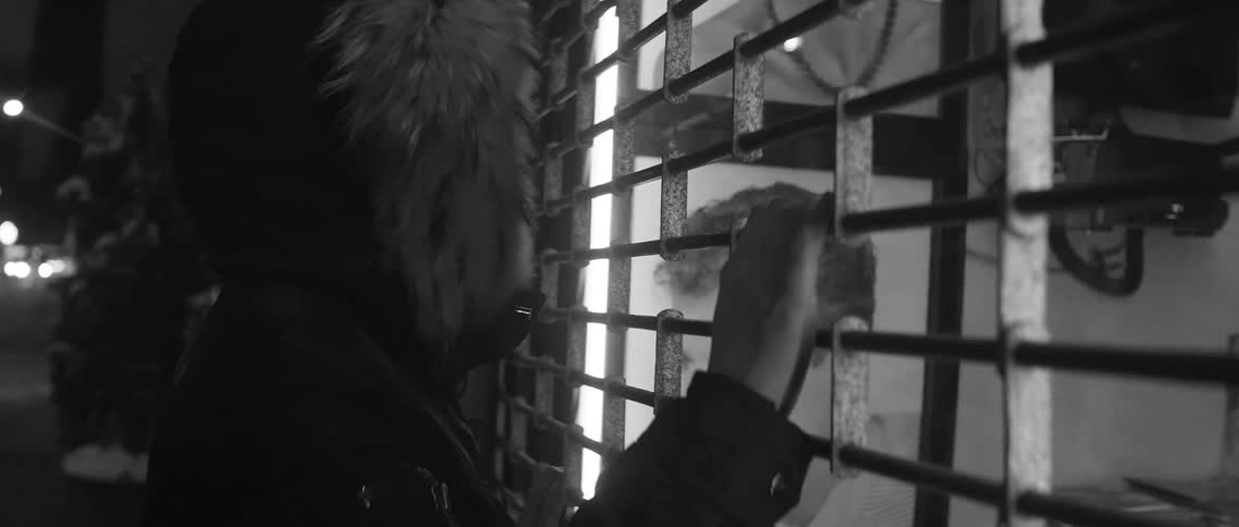 Person standing with hand on gate of closed shop