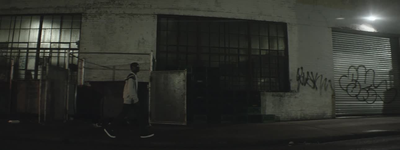 A boy walking by a graffitied building at night