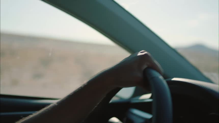 A person steering a car with one hand