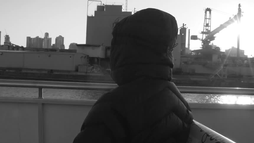 Man riding on a boat looks out at an industrial park