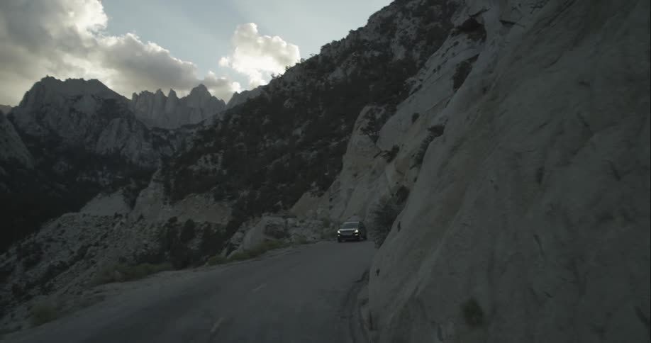 A car drives on a mountain road at dusk