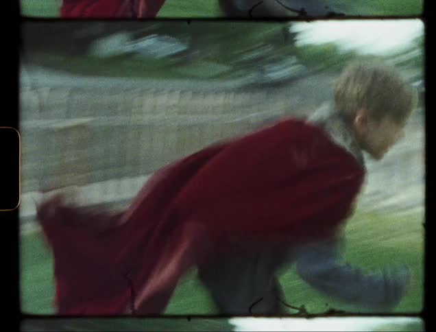 Small white dog chases a child in a cape