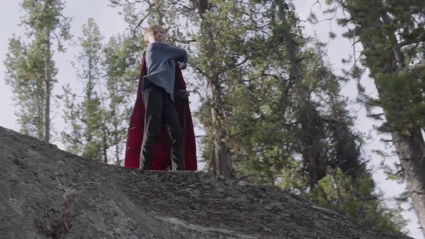 Child stands on a hill throwing rocks