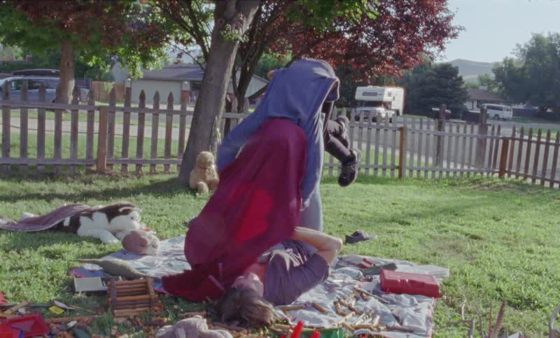 A woman is balancing her son on her feet as she lies in a yard on a sunny day