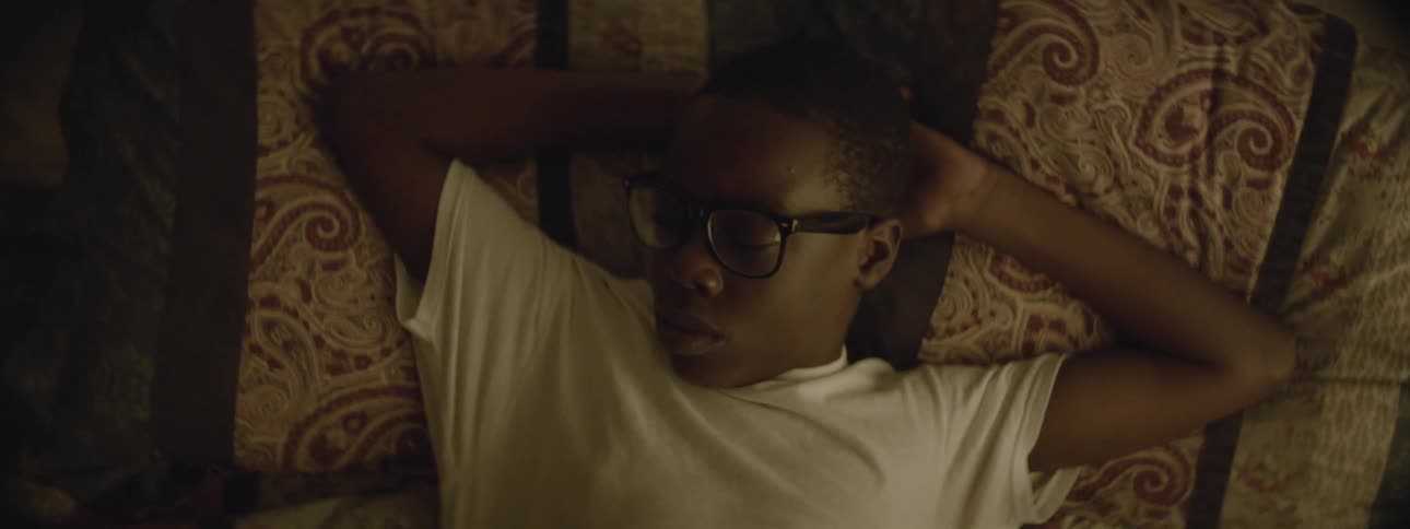 Boy lying on a bed opens his eyes and gets up