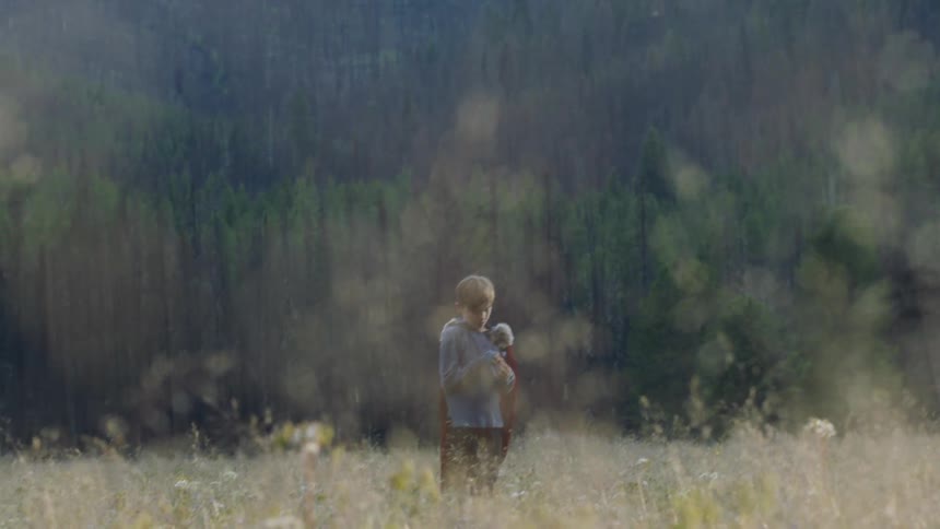 Boy picks up a stone in a rural field and throws it