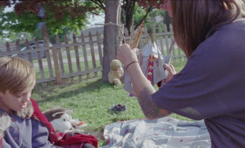Woman and boy in a costume sit on a front lawn