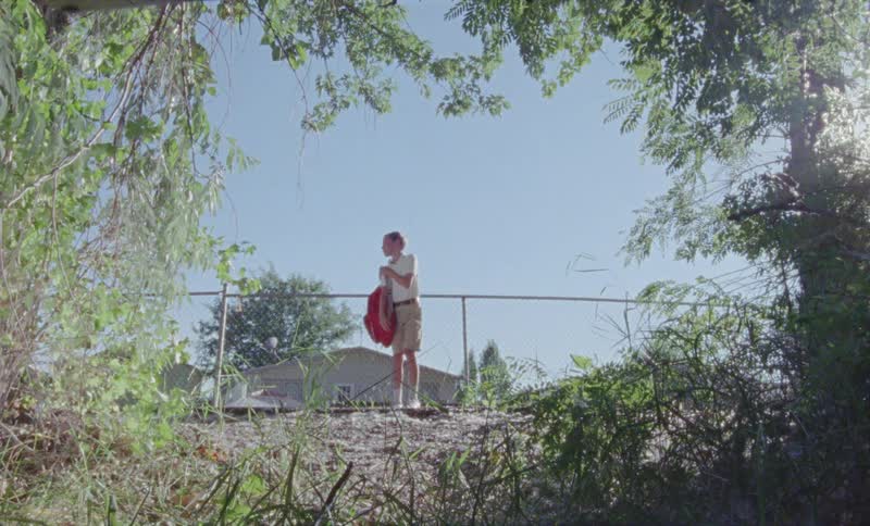 Boy takes off a backpack outside