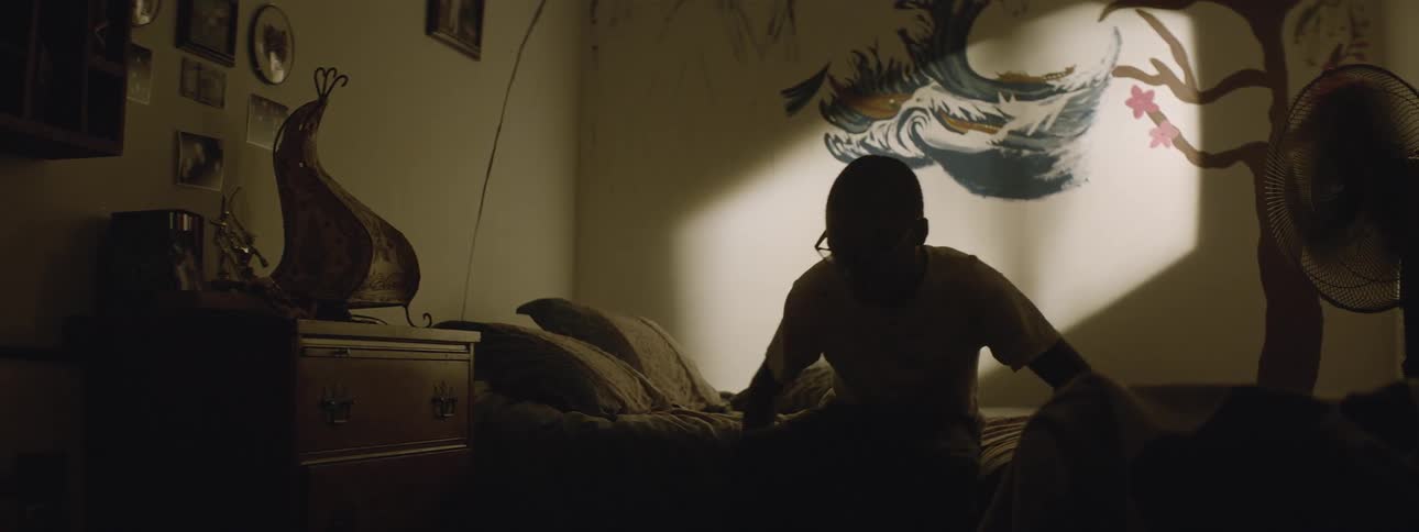 Boy gets off a bed in a dark room