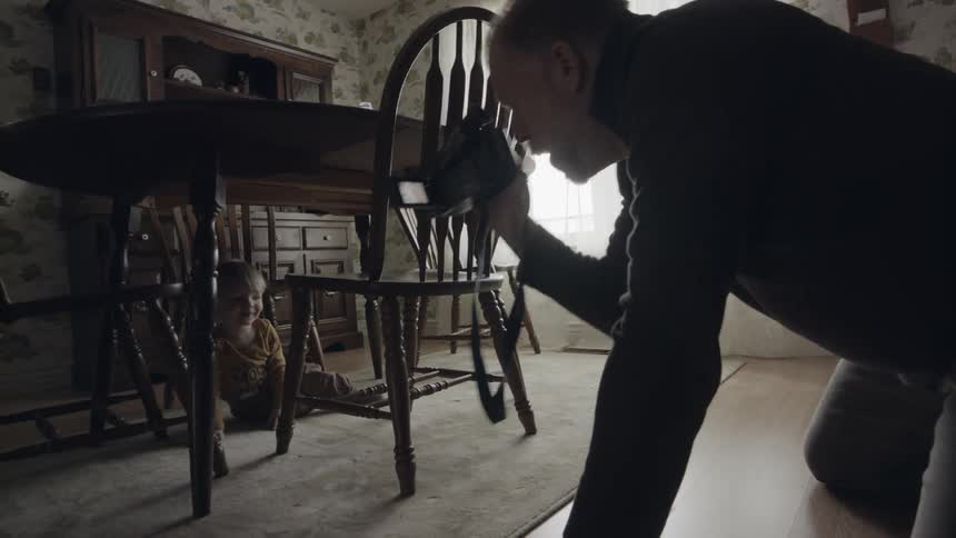 Man videotapes toddler playing under table