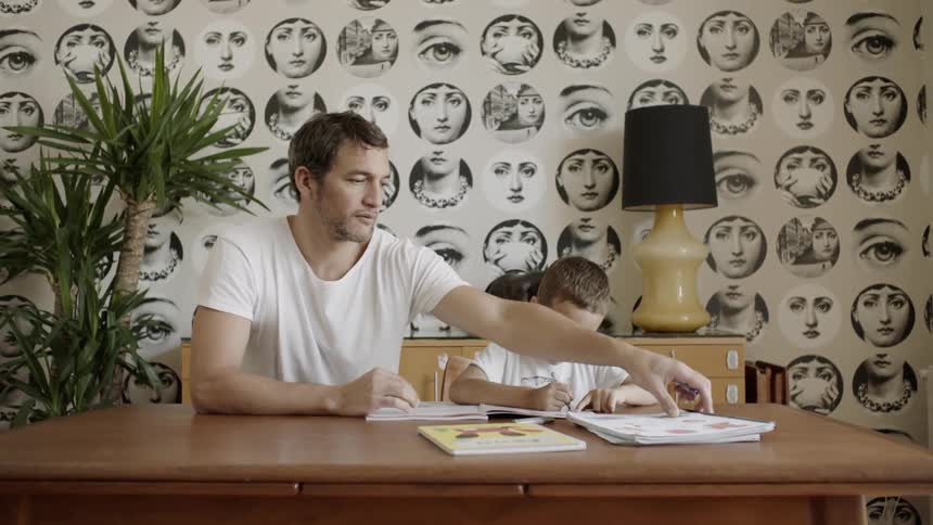 Man and child sit at table doing homework