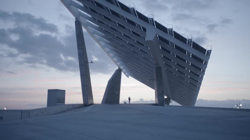 Woman runs under a large metal structure at sunset