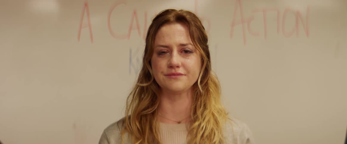 Woman cries in front of a white board with words written on it
