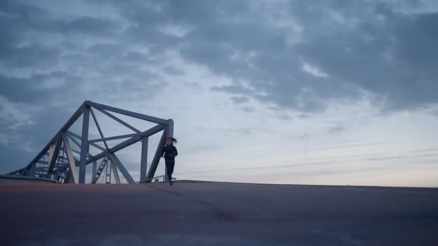 A woman runs downhill from the bridge