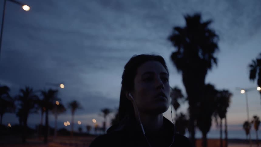 Woman jogs outside near the beach at night
