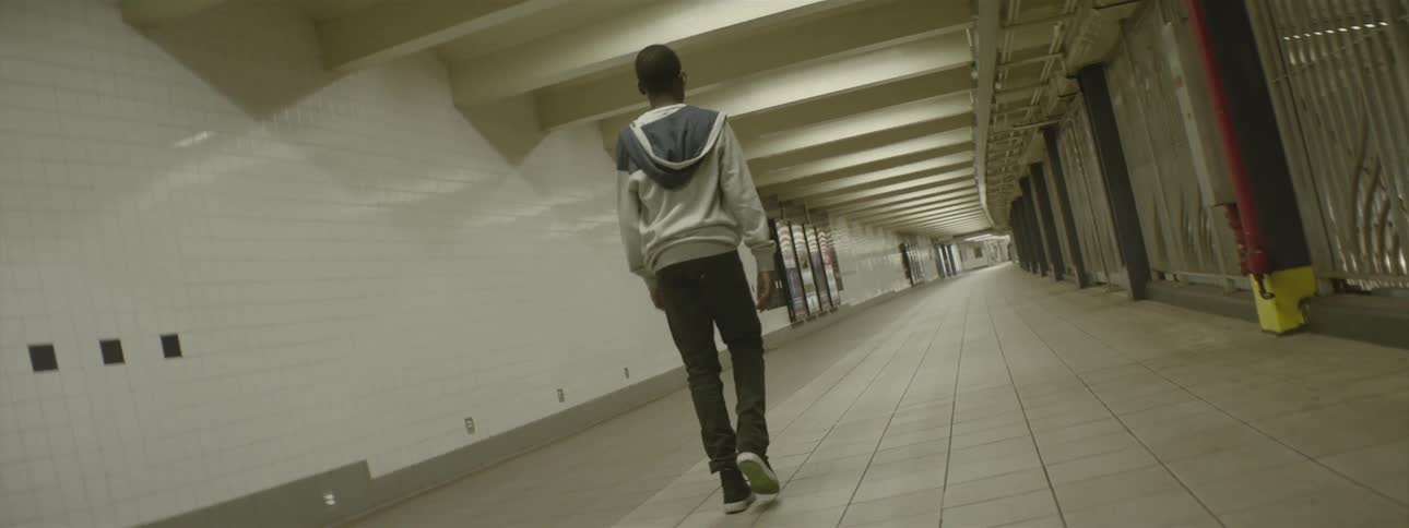Boy walking down a long hall in a subway