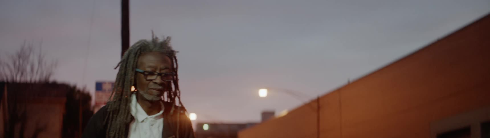 A man with dreadlocks walks on the street
