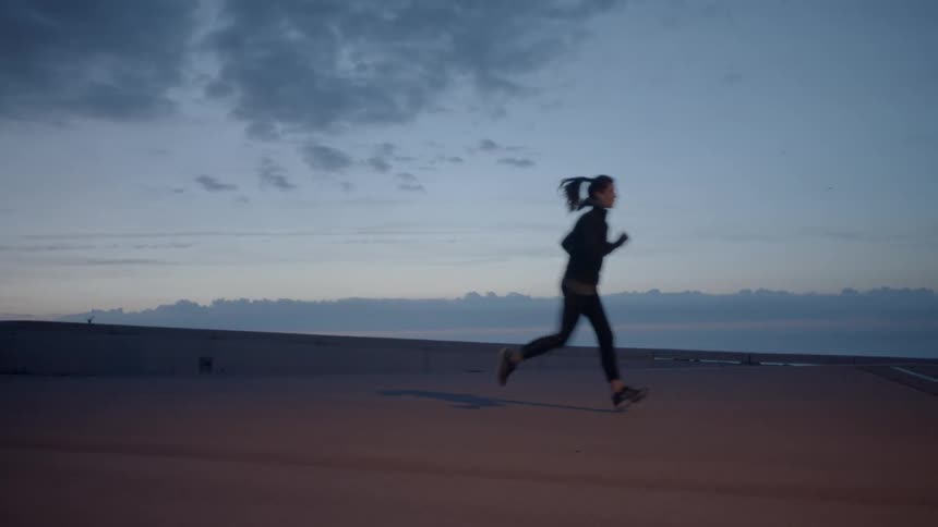 Woman jogs outside at sunset