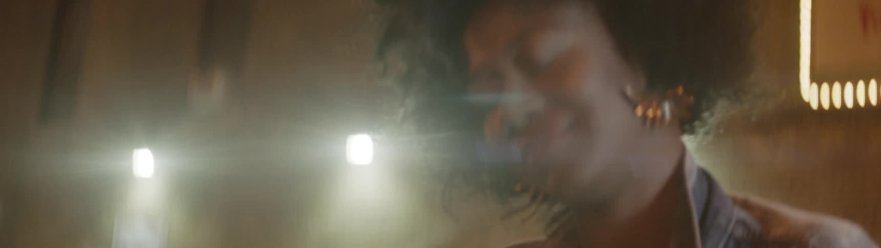 Woman smiles and sways her body with lights shining behind her