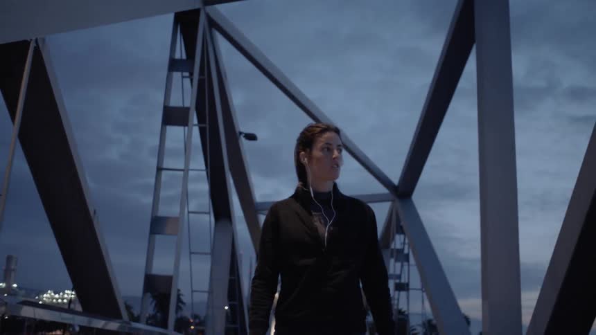 Woman walks on a bridge on a cloudy night