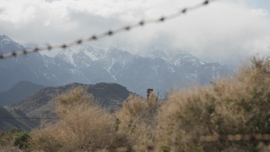 A barbed wire fence sits in mountains