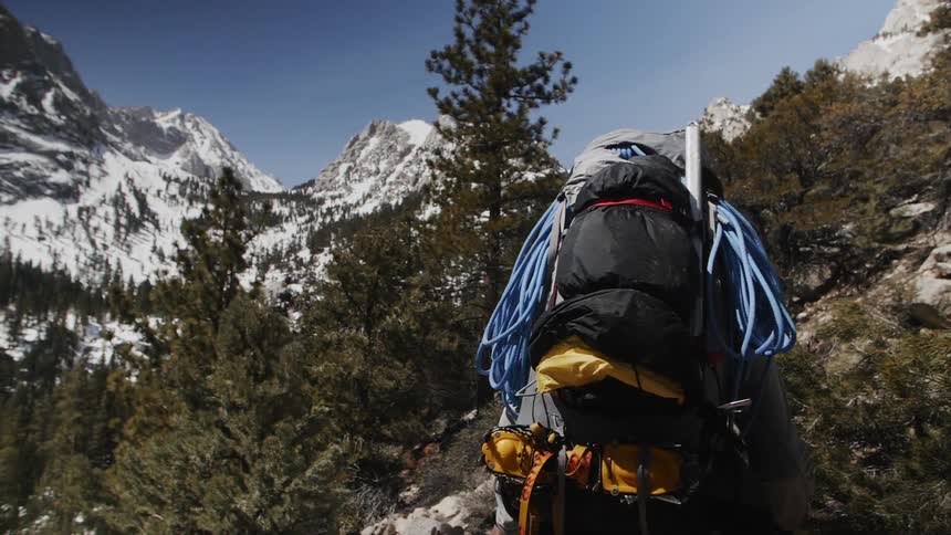 Person wearing a backpack hikes in snowy mountains