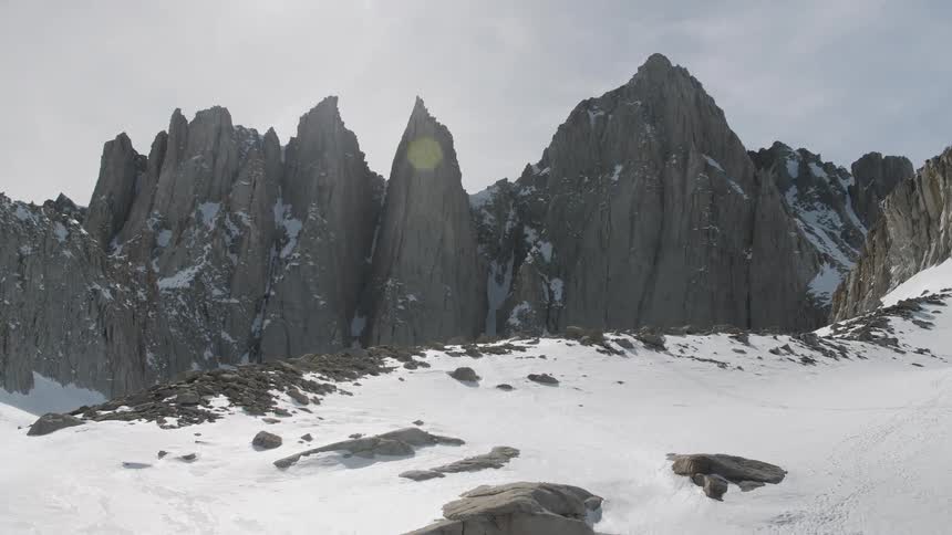 Sun shines down over rocky snowy mountains