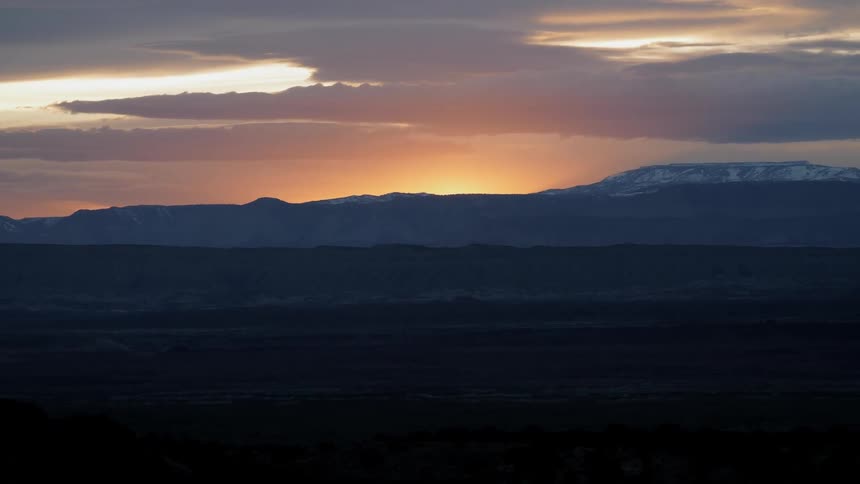 Sun sets behind snow covered mountains