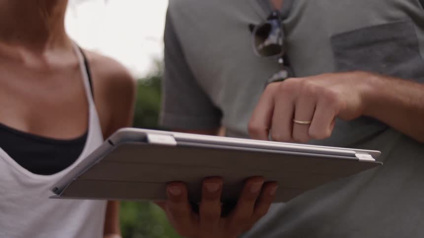 Person is scrolling on electronic tablet outside