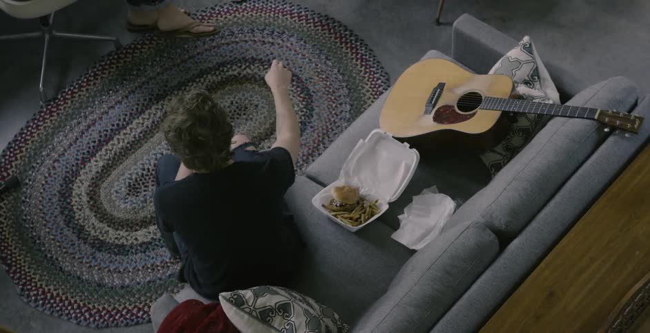 A man sits on a couch eating food