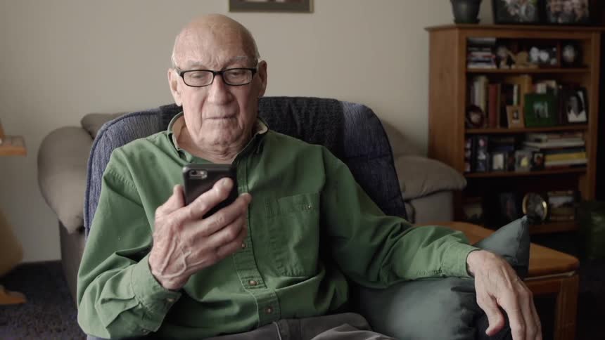 An elderly man uses a cell phone