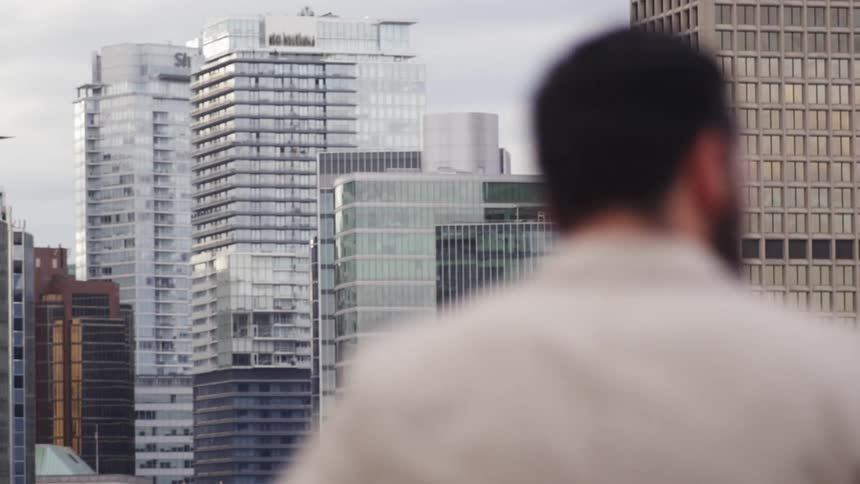 Man talks on a phone on a balcony outside in the downtown of a city