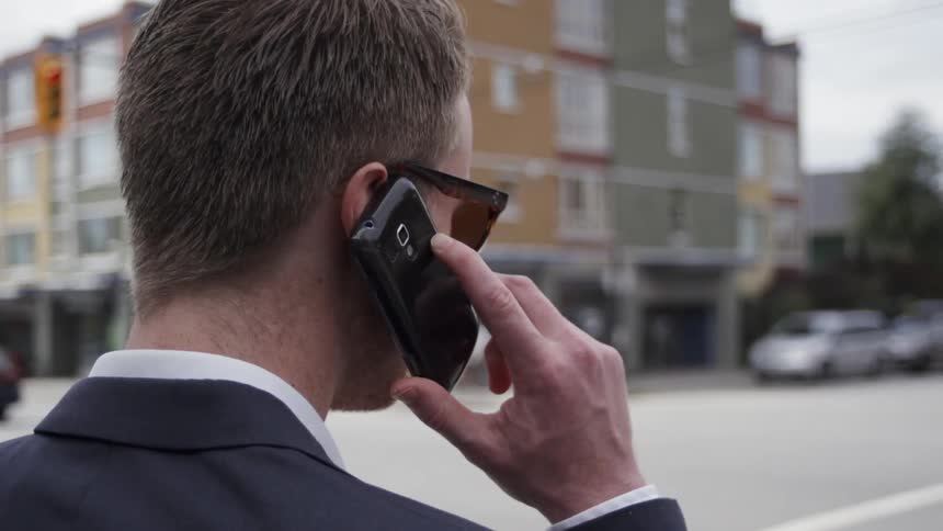 Man stands near urban street talking on phone
