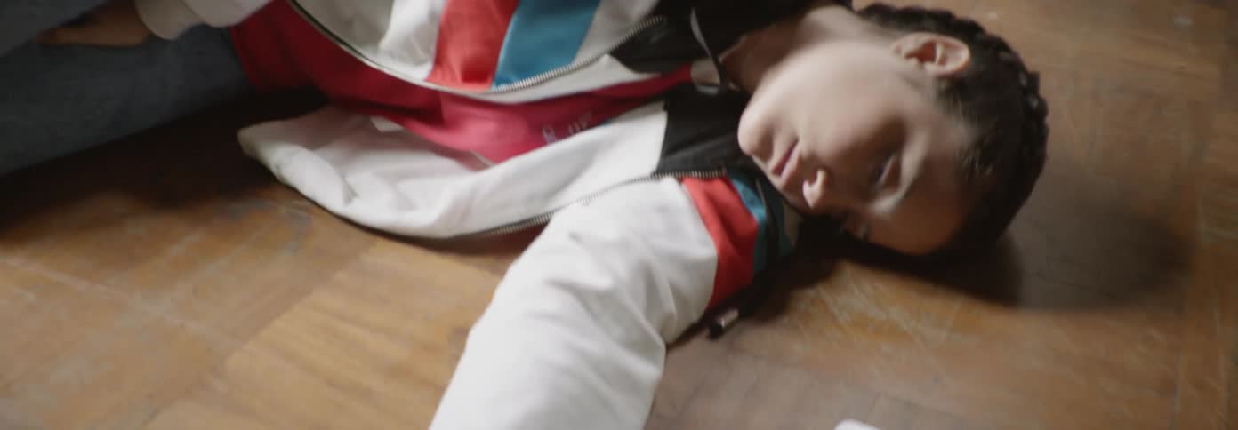 A teenage girl is lying asleep on the floor in a room in daylight