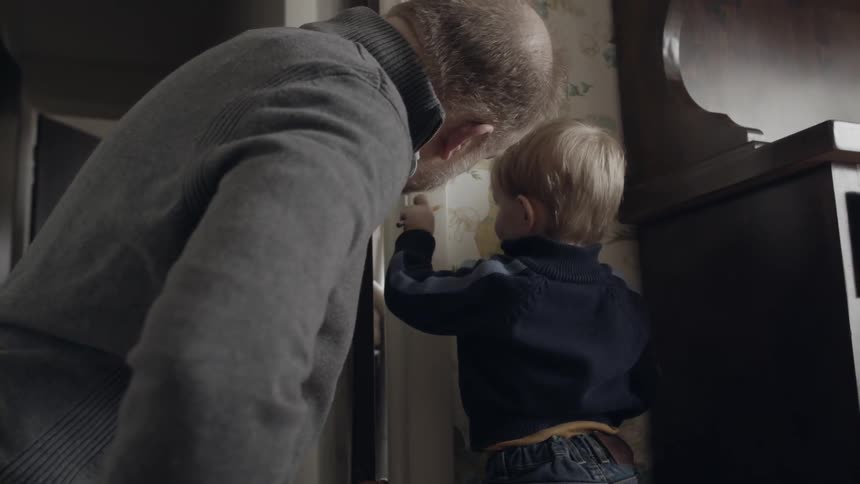 Man and child write on a doorway frame