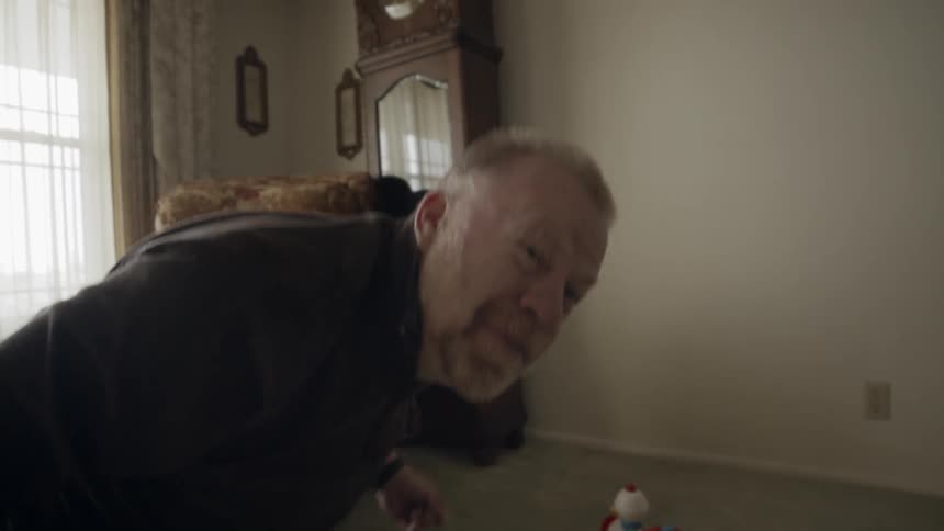 Man plays with a toy train on a living room floor