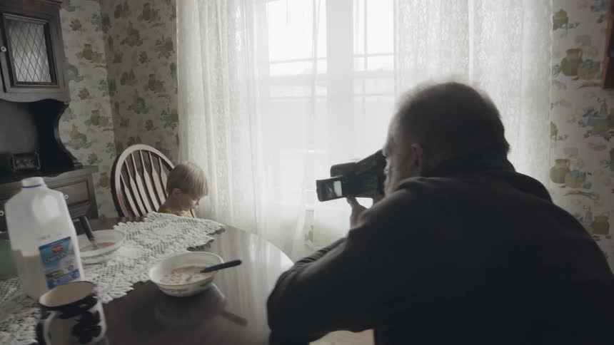 Man video records a baby sitting in a chair